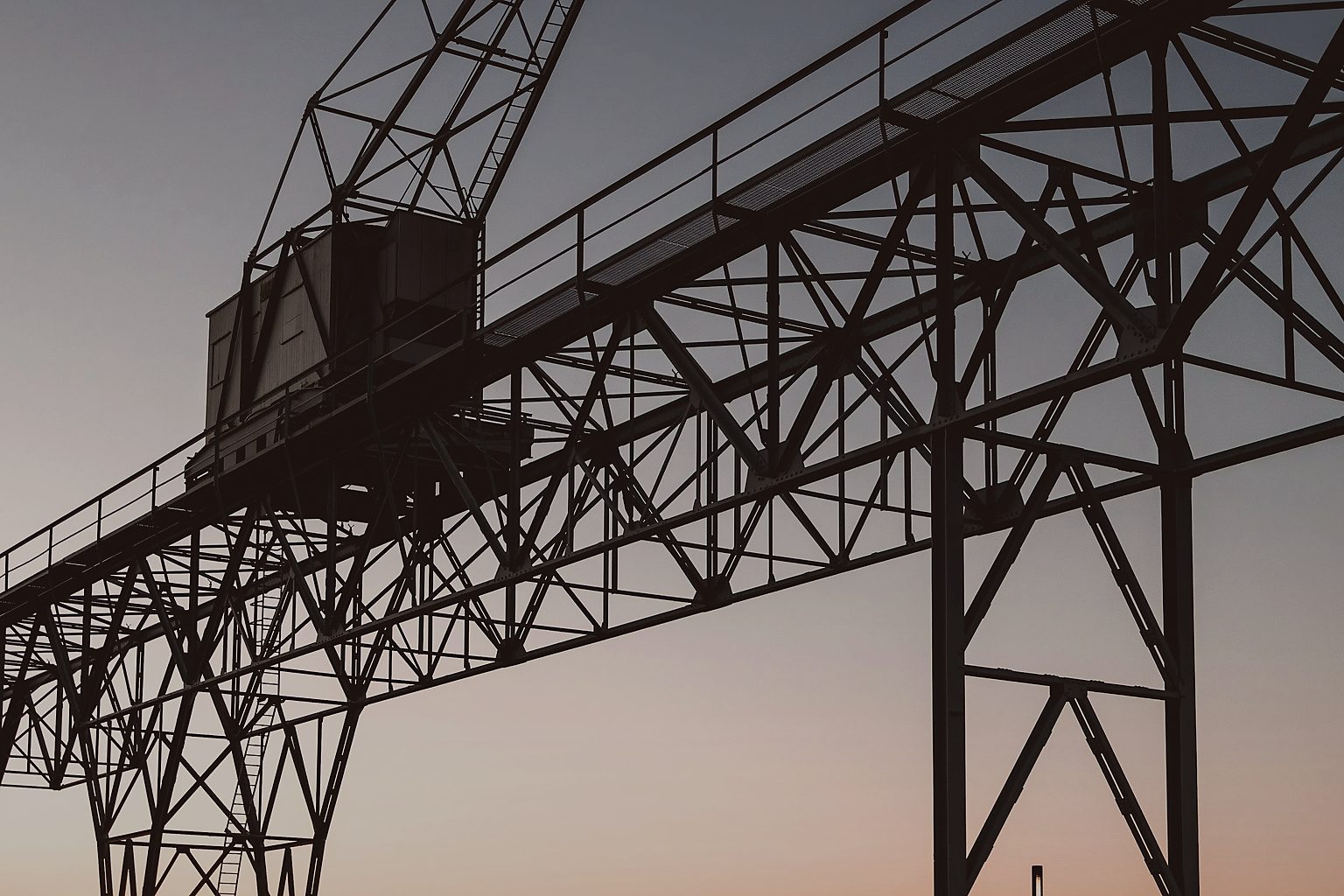 An industrial harbour crane silhouetted at sunset in Copenhagen.